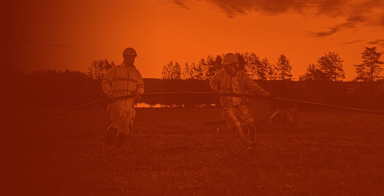 Two cable workers installing medium voltage cable in a field